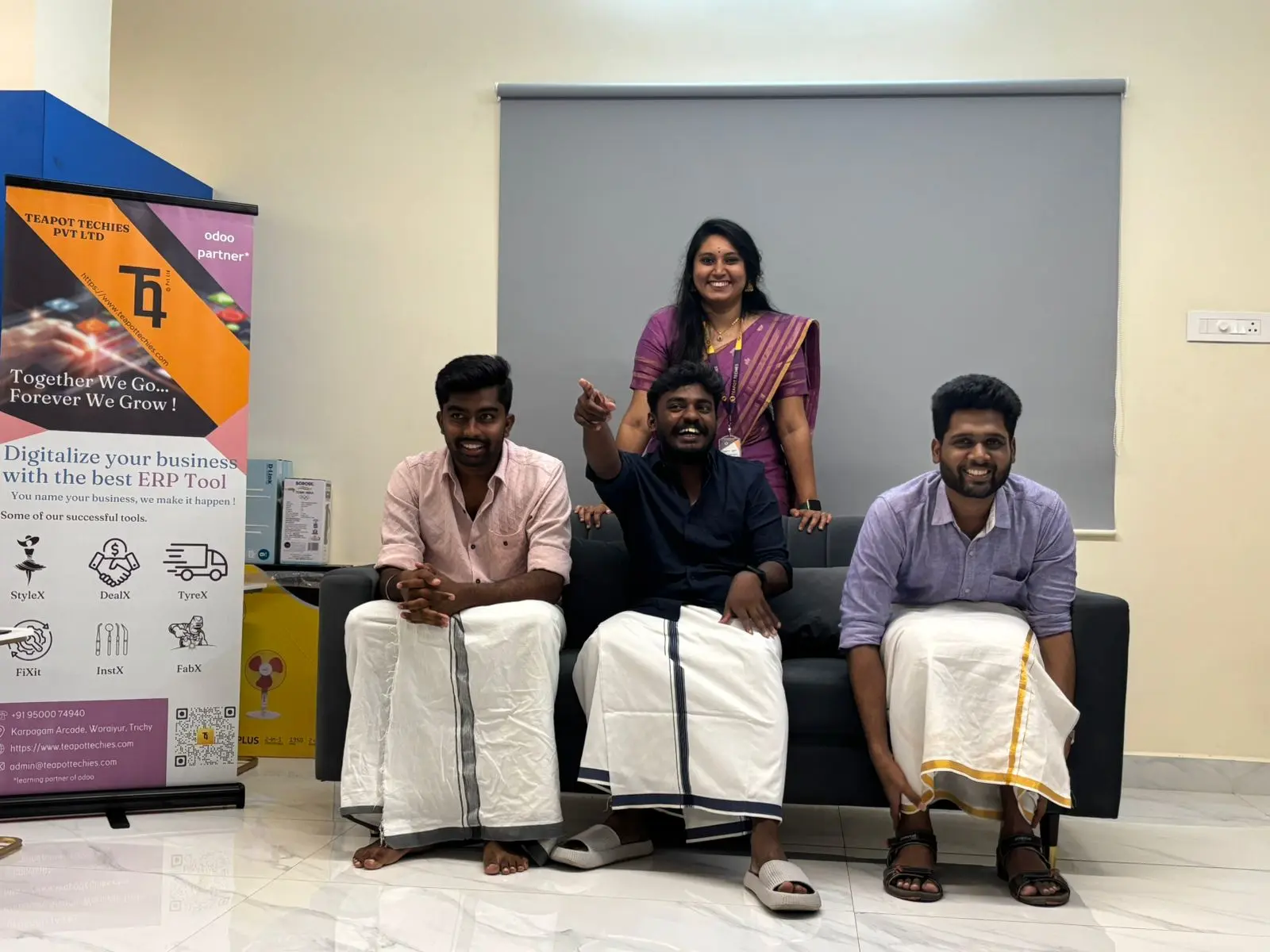 Team members smiling on the sofa beside a Teapot Techies banner