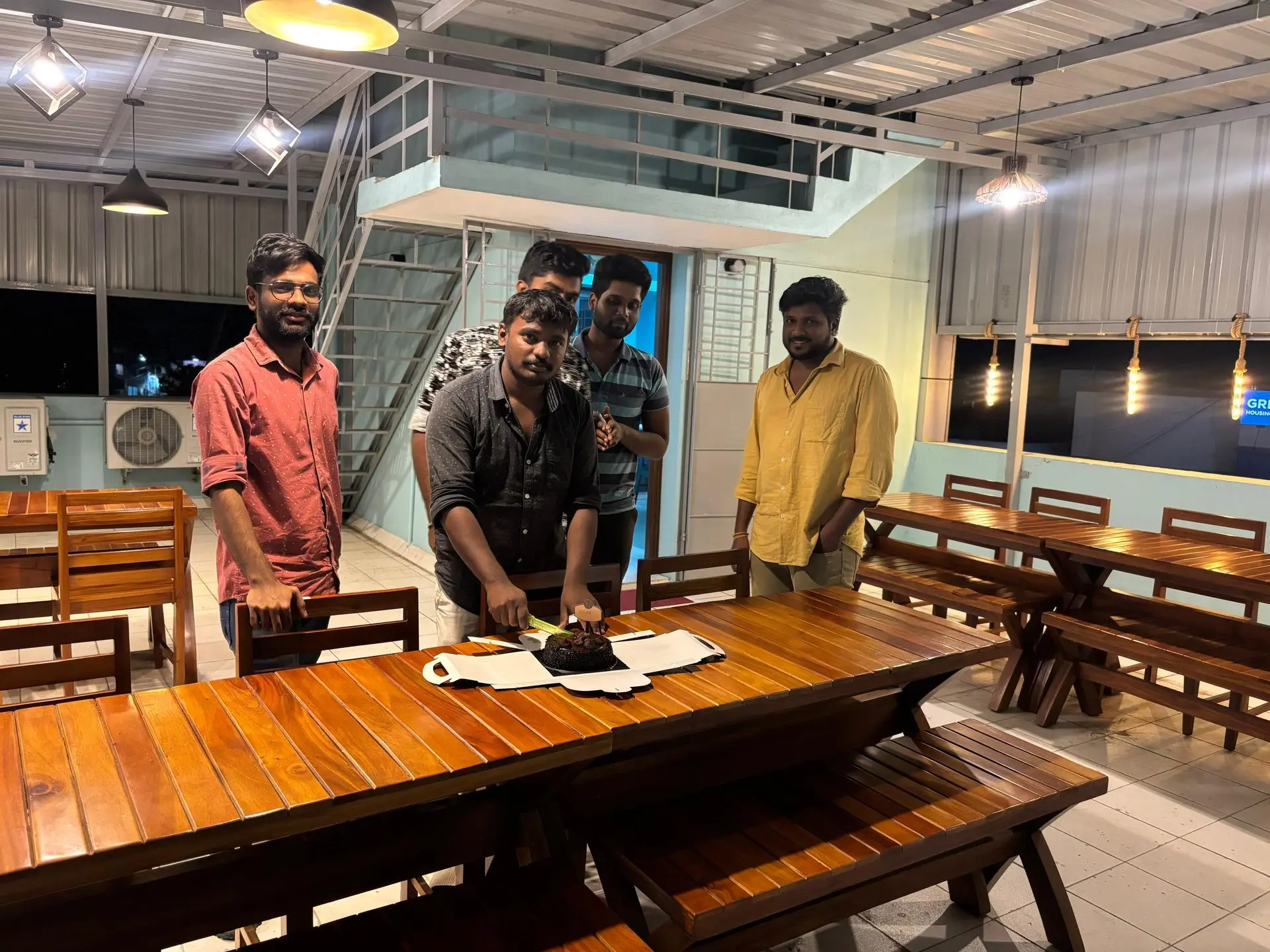 The team cutting a cake at the long wooden table