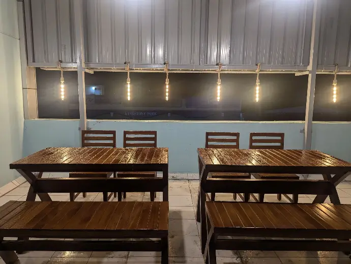 The wooden cafeteria tables lit by string lights